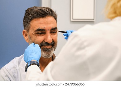 A man is getting ready to get Botox for crow's feet or laugh lines wrinkles by a aesthetic doctor in a clinic. - Powered by Shutterstock