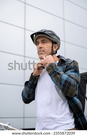 man getting ready to ride bicycle putting helmet on outdoors
