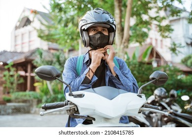 Man getting ready to wear helmet and mask on motorbike