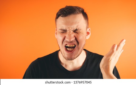 Man getting slapped on orange background. Unhappy scared man getting slapped standing on orange background