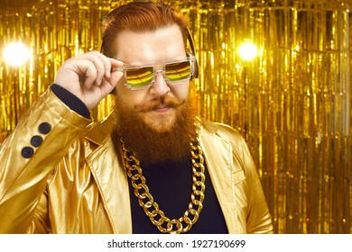 Man With Ginger Beard And Handlebar Moustache Putting On Cool Glasses. Serious Guy In Golden Outfit And Bling Chain Necklace Looking At Whats Going On At Concert Event. Retro Disco Party Style Concept