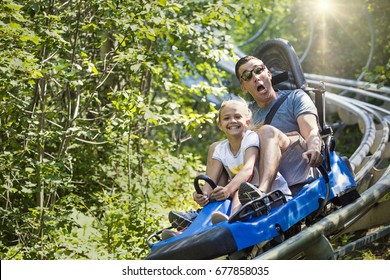Man and girl enjoying a summer fun roller coaster ride. They have some funny expression as they enjoy a thrilling ride on a red amusement park ride