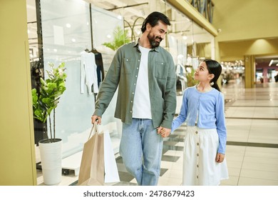 A man and a girl happily walk through a bustling mall, carrying shopping bags filled with their weekend finds. - Powered by Shutterstock