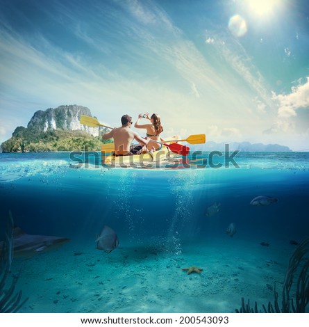 Man and girl kayaking next to a tropical island 