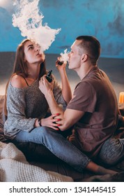 man and girl smoking in bed electronic cigarettes vape-mod and drip. Couple vaping.