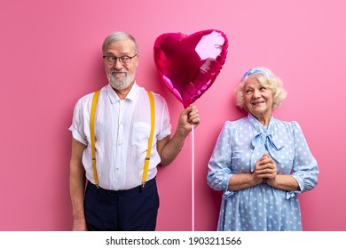 Man Give Heart Shaped Balloon As Present To Mature Happy Woman, Make Surprise To Wife. Isolated Pink Background