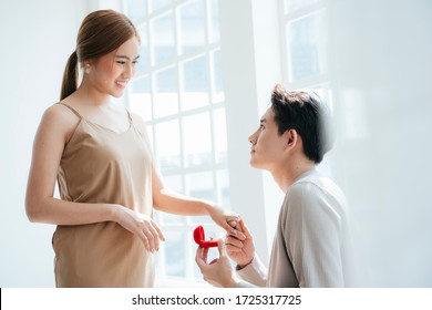 A man give a woman the wedding ring in red box and asking her, will you marry me. - Powered by Shutterstock