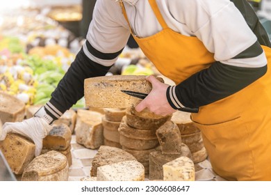 A man gives a cheese tasting to his customer. Cheese tasting. Cheese is cut with a special cheese knife. - Powered by Shutterstock