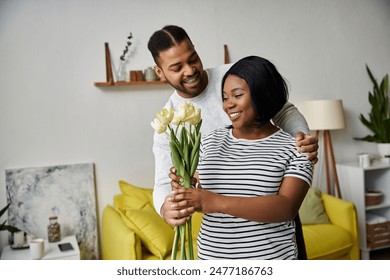 A man gives his wife a bouquet of flowers at home. - Powered by Shutterstock