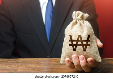 Man gives a south korean won money bag. Loan issuance. Financial support, leasing. Funding. Accounting tax payment. Earnings and profits. Investments, financing Lobbying. Stimulating economic recovery