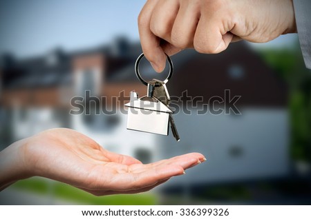 Man gives a woman the keys to a new home. Chrome pedant with house shape