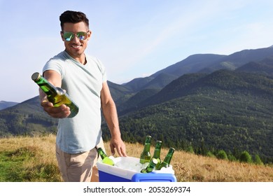 Man Giving Bottle From Cool Box In Mountains. Space For Text