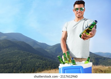 Man Giving Bottle From Cool Box In Mountains. Space For Text