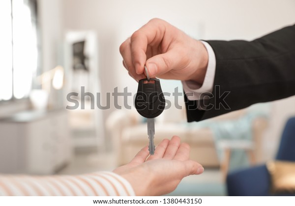 Man giving car key to woman indoors, closeup. Space\
for text