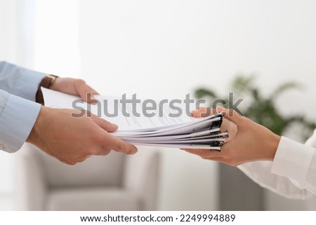 Man giving documents to colleague in office, closeup