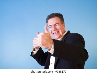 A man giving and elated "thumbs up" taken against a blue background.