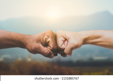Man giving fist bump in sun rising nature background. power of teamwork concept. vintage tone - Shutterstock ID 1131885767