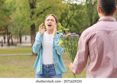 Man giving flowers to his allergic girlfriend outdoors - Powered by Shutterstock