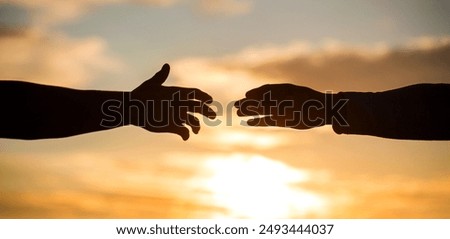 Man giving hand to man outdoors at sunset, closeup. Help and support concept. Closeup helping hands on the sunset sky background. Rescue Help.