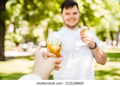 Man Giving Ice Cream In Hot Sunny Day In City Park. First Person Point Of View Reach Out Hand