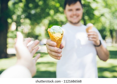 Man Giving Ice Cream In Hot Sunny Day In City Park. First Person Point Of View Reach Out Hand