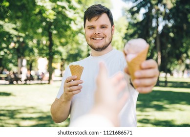 Man Giving Ice Cream In Hot Sunny Day In City Park. First Person Point Of View Reach Out Hand