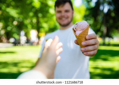 Man Giving Ice Cream In Hot Sunny Day In City Park. First Person Point Of View Reach Out Hand