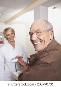 Man Giving Insurance Card To Female Doctor Smiling Looking At Camera