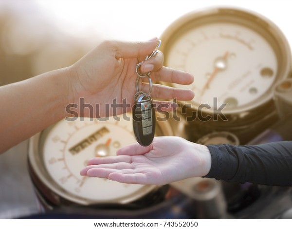 Man giving key to woman on blur motorcycle\
background, financial\
concept.