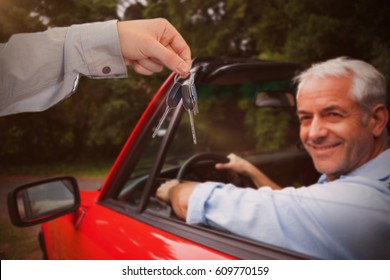 Man Giving Keys To Someone Against Smiling Man Driving Red Car