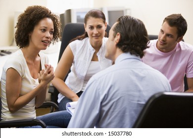 Man giving lecture to three people in computer room