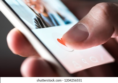Man giving a like to photo on social media or swiping on online dating app. Finger pushing heart icon on screen in smartphone application. Friend, follower or fan liking picture of a beautiful woman.  - Shutterstock ID 1204256551