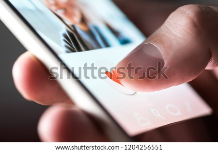 Man giving a like to photo on social media or swiping on online dating app. Finger pushing heart icon on screen in smartphone application. Friend, follower or fan liking picture of a beautiful woman. 