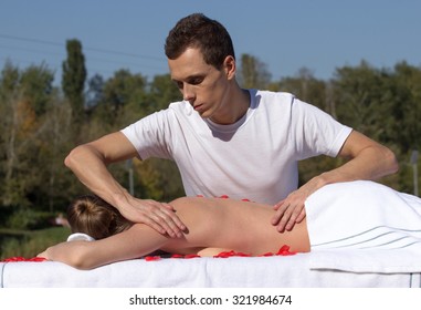 Man giving massage to young brunette outdoors sunny day - Powered by Shutterstock