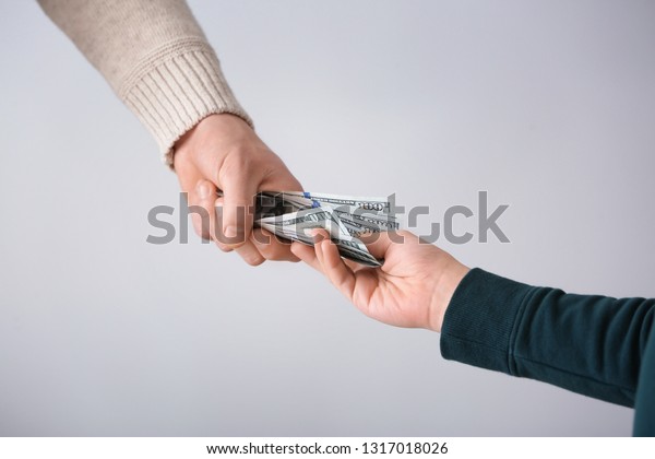 Man giving money to his son on light background.\
Concept of child support