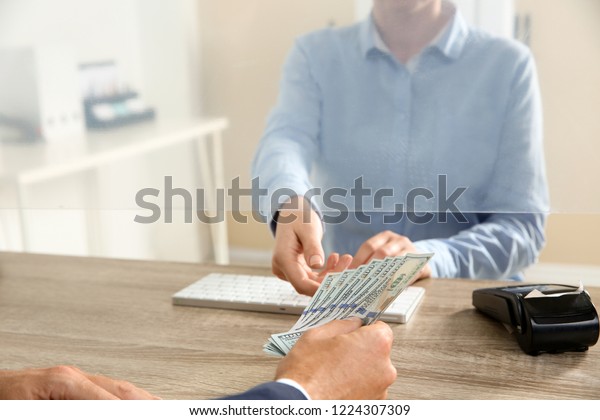 Man giving money to teller at cash department\
window, closeup