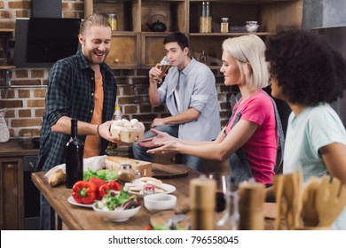 man giving mushrooms to multiethnic friends who cooking - Shutterstock ID 796558045