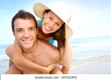 Man giving piggyback ride to girlfriend by the ocean