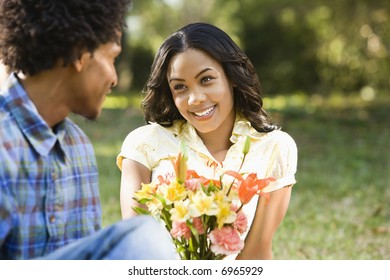 Man Giving Smiling Woman Bouquet Of Flowers.