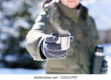 Man giving steamy coffee from thermos. Winter picnic in snowy wonderland. Traveler drinking tea and holding metal cup. Offer hot beverages. Lifestyle moment in nature. Close up of hands in gloves - Powered by Shutterstock