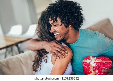 Man Giving A Surprise Gift To Woman At Home