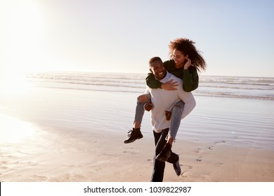 Man Giving Woman Piggyback On Winter Beach Vacation - Powered by Shutterstock