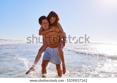 Man Giving Woman Piggyback On Summer Beach Vacation
