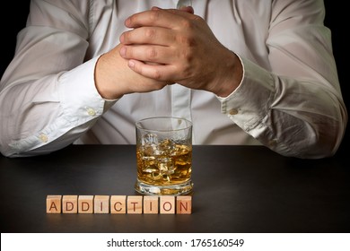 Man with a glass of Scotch and ice and the word addiction. Concept of social problems