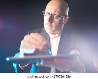 A man with glasses is holding an electronic tablet and a stylus. Computer gadgets. Modern communication technologies. Getting information from the Internet. Making orders online. - Shutterstock ID 1707564556