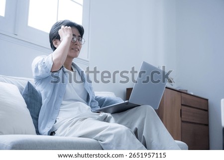 A man with glasses looking at a computer, apologizing while talking on his phone.	