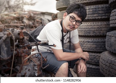 man with glasses in metal scrap junk yard surrounding with vehicle and engine parts, tires and metal scrap. He hold DSLR camera like foreigner tourist. - Powered by Shutterstock