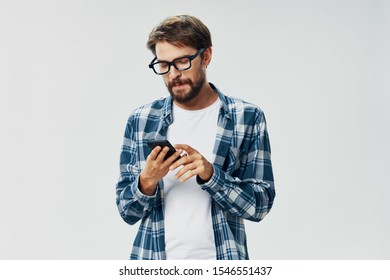 Ein Mann mit Brille und einem geputzten Hemd sieht sich das Handy in der Hand an