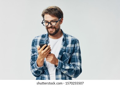 A man with glasses a plaid shirt and a mobile phone glasses