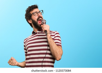 Man with glasses singing with microphone on colorful background